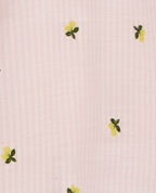 Primer plano de tela de pijama batola rosa con rayas blancas finas y bordado de limones amarillos St. Even.