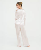 Pijama para mujer en satín marfil con camisa de manga larga y pantalón largo de ajuste relajado.
