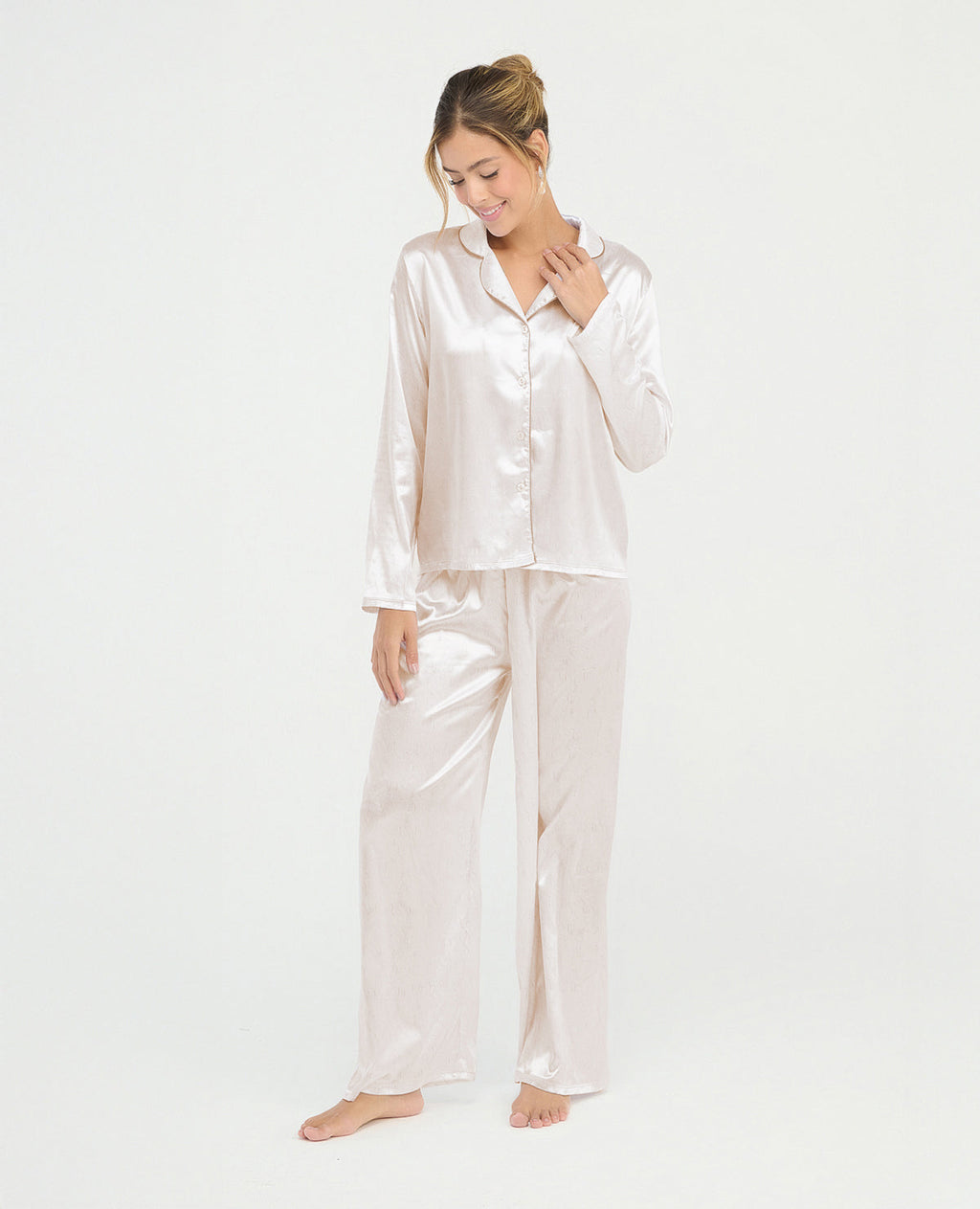 Pijama para mujer en satín marfil con camisa de manga larga, cuello clásico y pantalón largo de ajuste relajado.