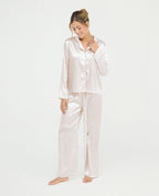 Pijama para mujer en satín marfil con camisa de manga larga, cuello clásico y pantalón largo de ajuste relajado.