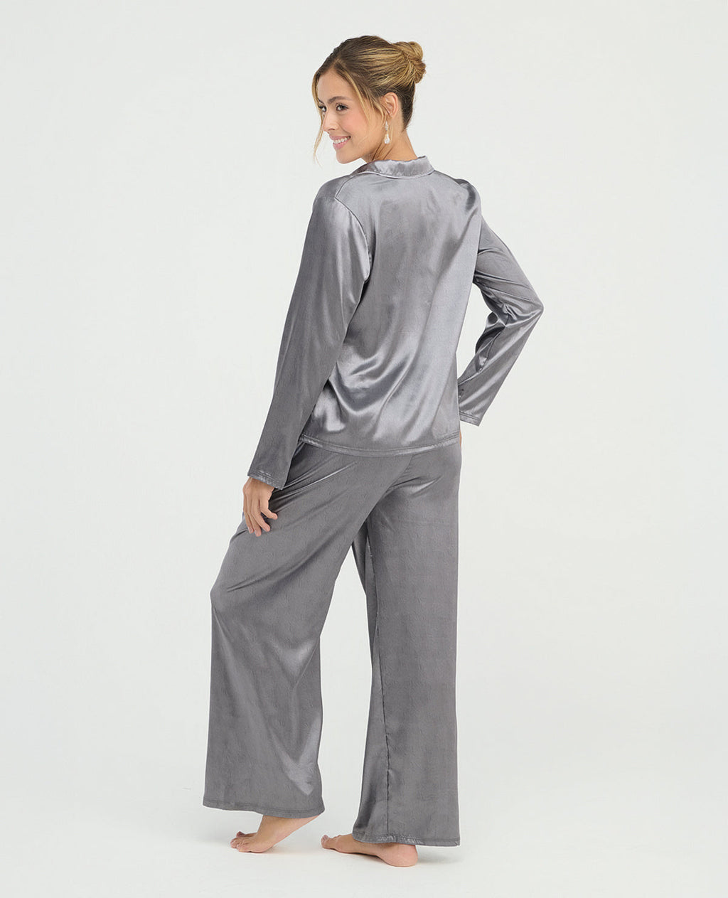 Mujer usando pijama de satín gris de pantalón y camisa manga larga, vista posterior con textura brillante y suave.