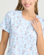 Mujer usando pijama batola azul claro con estampado de perros, cuello redondo y manga corta en tejido piel de durazno.
