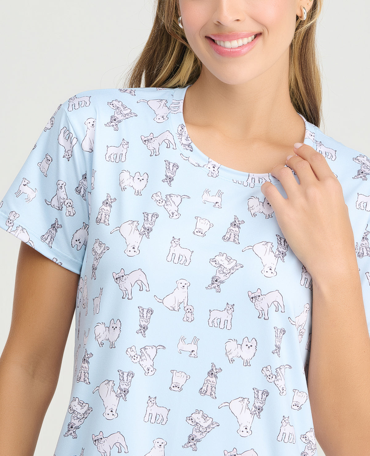 Mujer usando pijama batola azul claro con estampado de perros, cuello redondo y manga corta en tejido piel de durazno.
