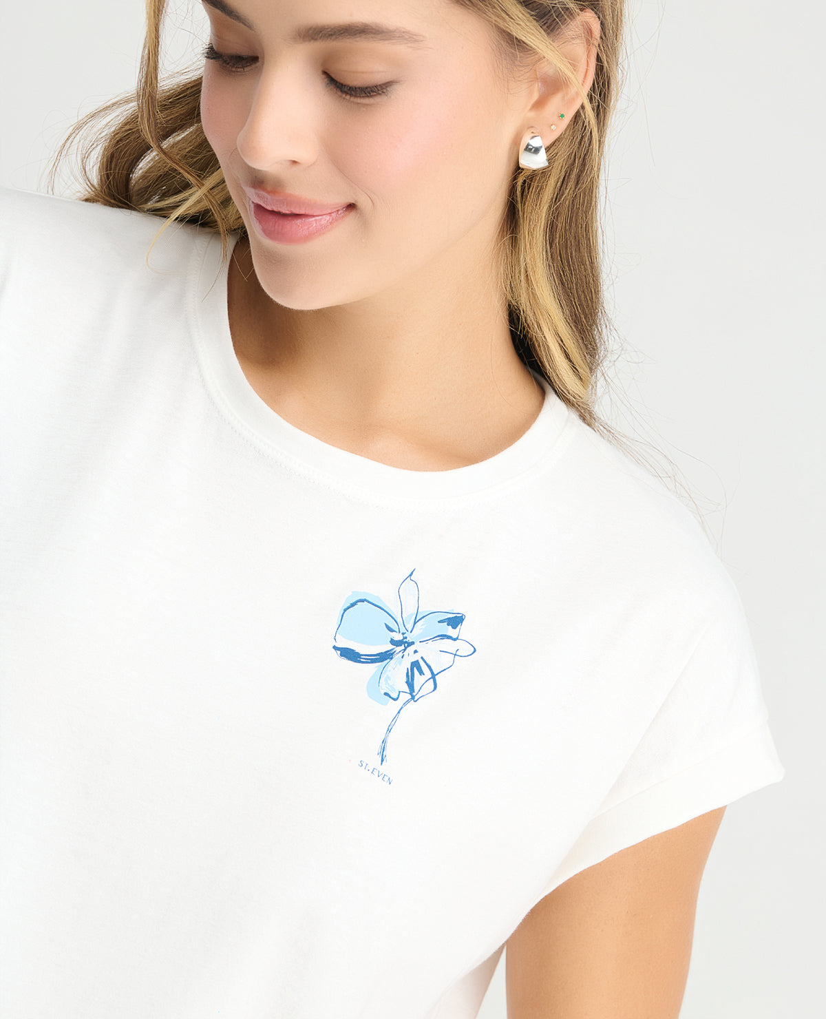Primer plano de camiseta blanca de pijama para mujer con cuello redondo y estampado de flor azul sutil.