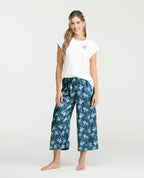 Pijama de mujer con camiseta blanca de cuello redondo y pantalón capri satinado azul con estampado floral.