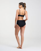 Vista posterior de modelo usando brasier negro con espalda lisa sin broches y cargaderas ajustables.