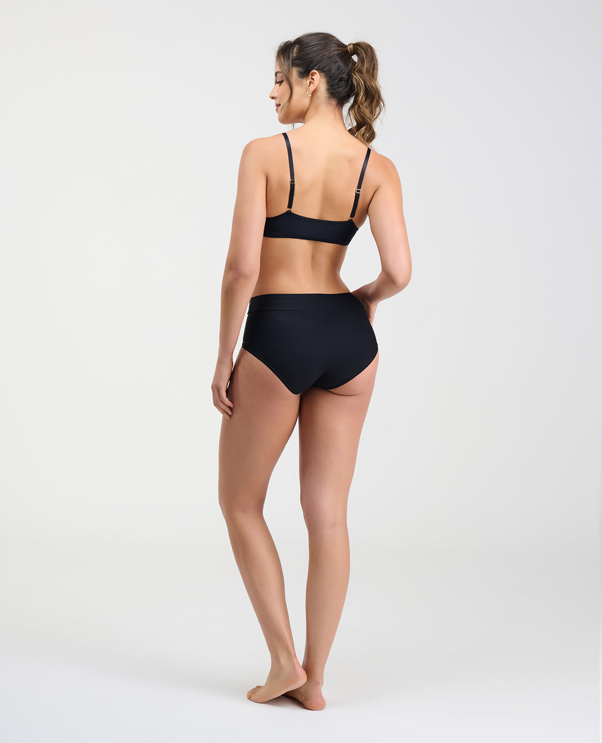 Vista posterior de modelo usando brasier negro con espalda lisa sin broches y cargaderas ajustables.