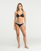 Brasier negro con broche frontal dorado, realce natural y escote profundo con estampado de puntos blancos.
