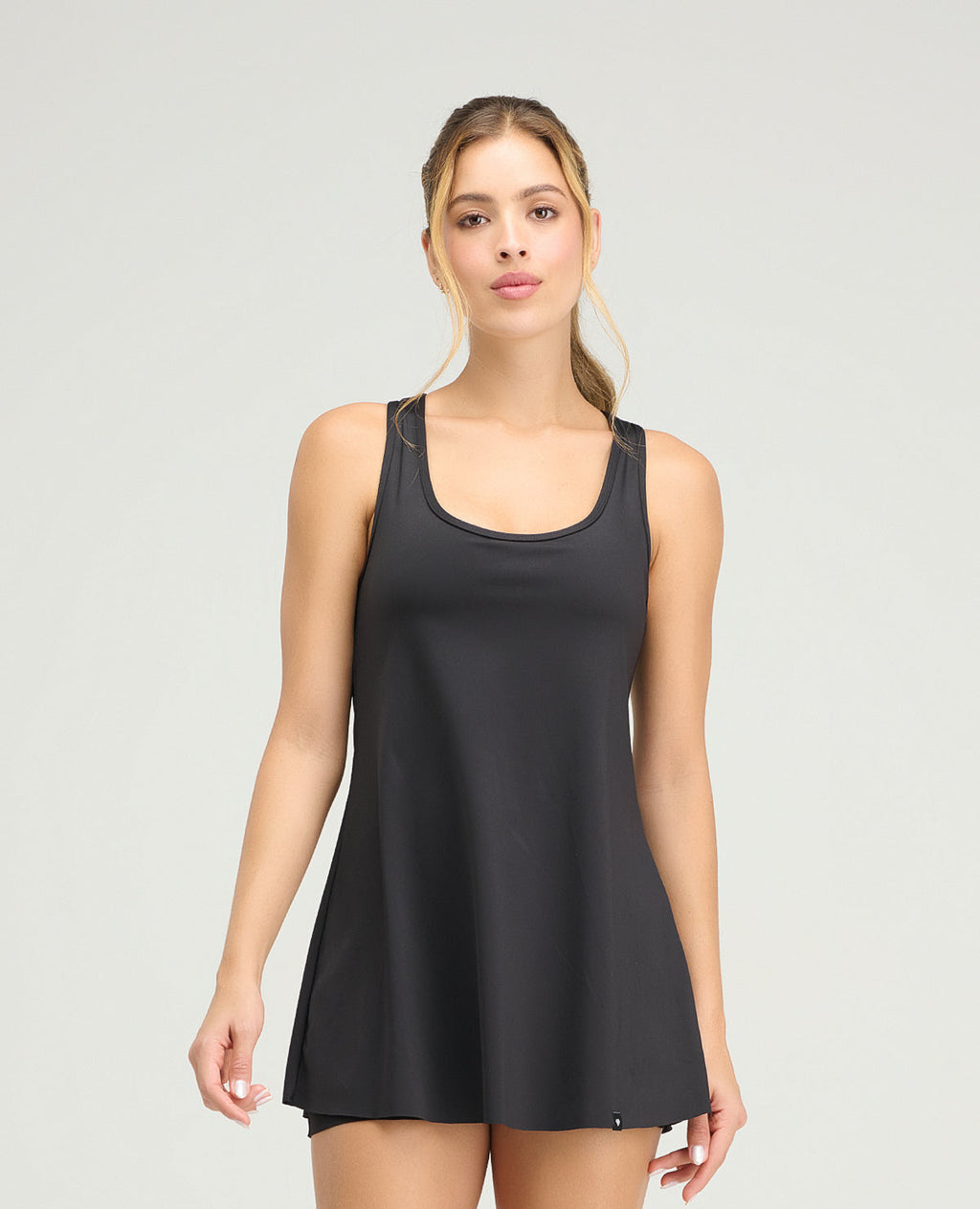 Mujer usando vestido deportivo negro de silueta semi-ajustada con short interior y acabado de corte limpio.