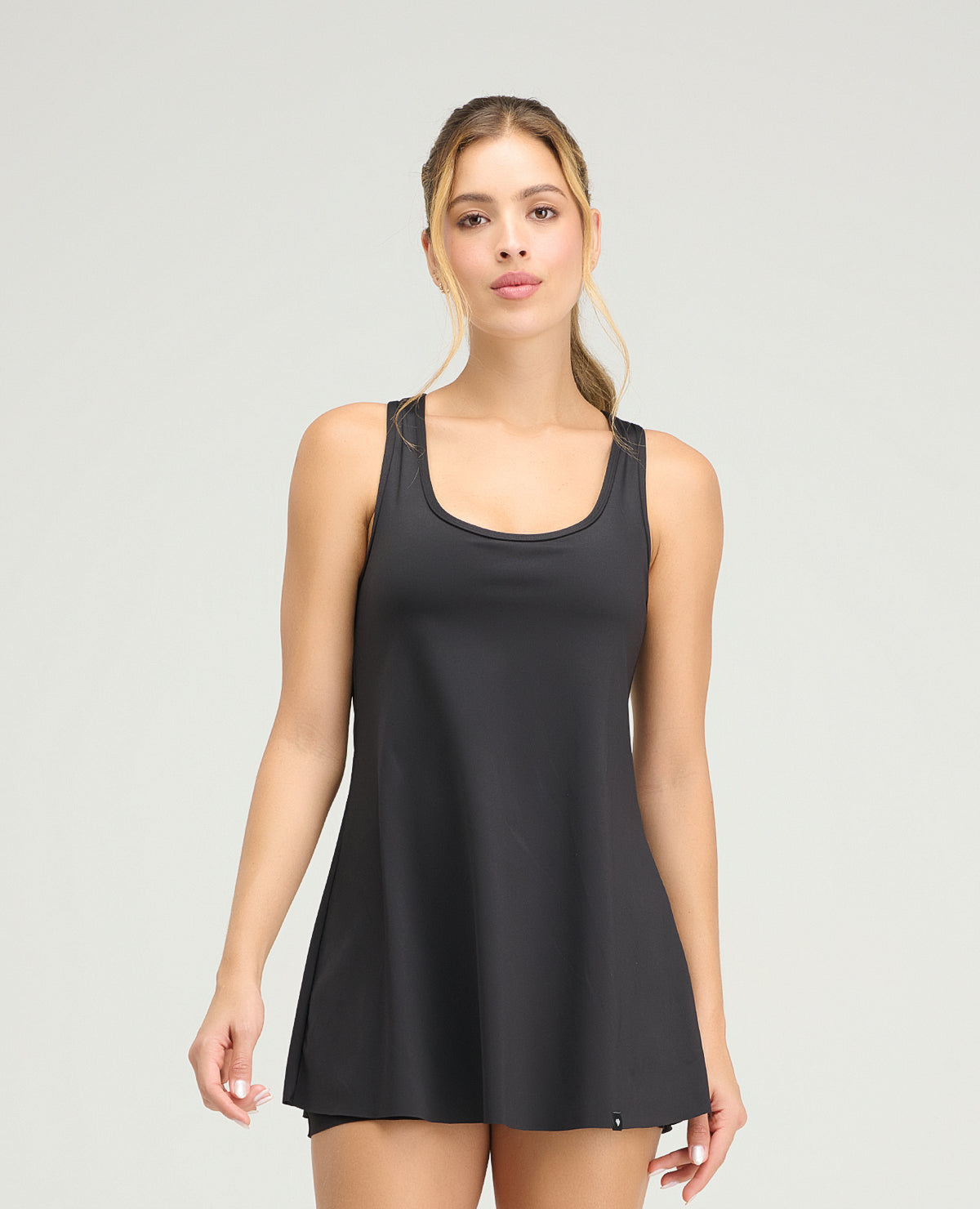Mujer usando vestido deportivo negro de silueta semi-ajustada con short interior y acabado de corte limpio.