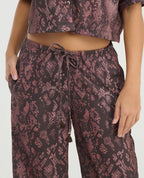 Primer plano de pantalón de corte recto con estampado animal, pretina elástica y tiras ajustables con borlas.