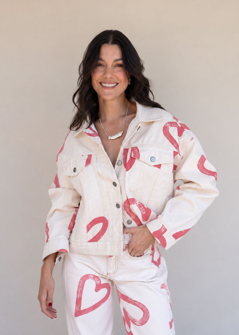 Ivory cotton drill denim jacket with all-over red heart print, front pockets, and barrel sleeves