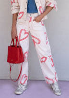 Ivory cotton drill jean with all-over red heart print, wide leg, side cuts, and knee darts