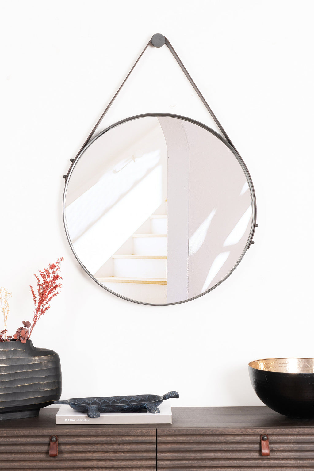 Sleek round Boston Mirror with a sturdy steel frame and elegant leather strap, perfect for adding modern charm to any room.