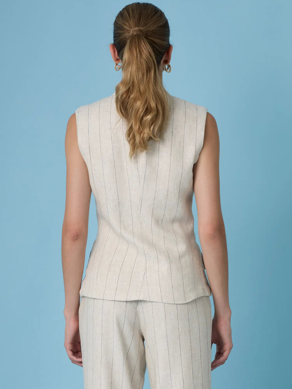Blusa Rondine Sand elegante en beige con rayas delgadas, bolsillos decorativos y diseño sin mangas moderno.