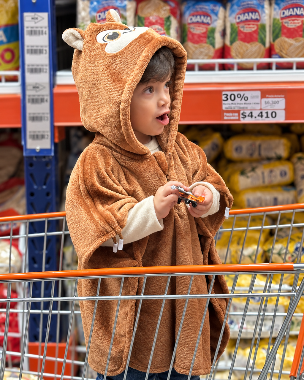 Ruana Ardilla café de Dosmicos: vista frontal de la capota y el frente, usada por un niño durante una salida al supermercado.
