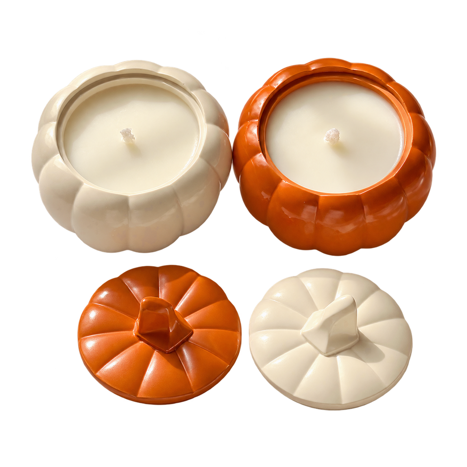 Cream and orange Pumpkin Charm candles in pumpkin-shaped jars, shown with matching lids beside them.