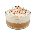 Tres Leches candle in a glass bowl, with cream-colored swirls and red and green round decorations.